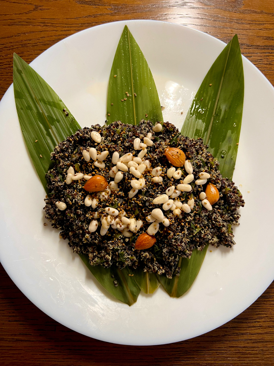 Черная крупа киноа с кедровыми орехами, абрикосовыми косточками и люцерной на листьях бамбука как вариант сервировки