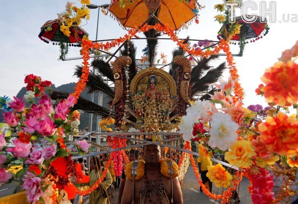 Мужчина празднует Тай Пусам, неся на себе алтарь Бога