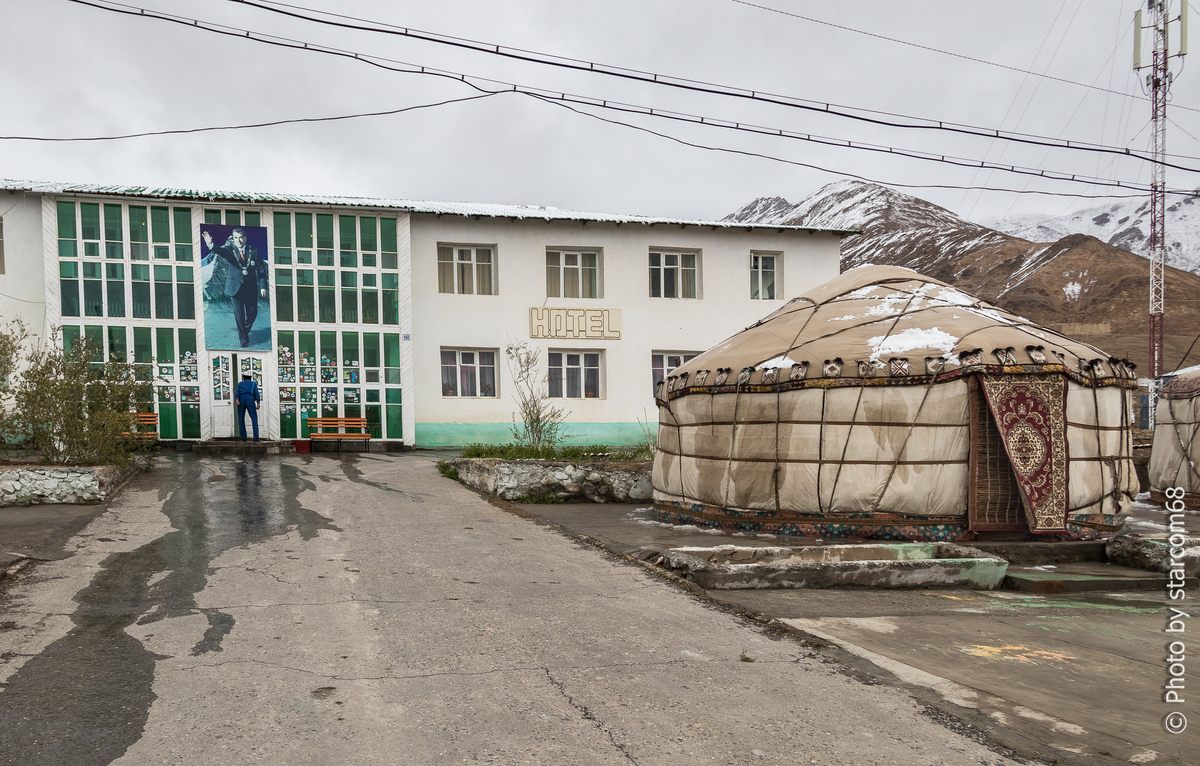 Гостиница "Pamir" в Мургабе. На фасаде плакат с Основателем мира Эмомали Рахмоном, вскидывающем руку в "салюте Беллами", но тогда про это мало кто знал. Двери и стекла фасада обклеены наклейками многочисленных путешественников. Я про эту традицию не знал и поэтому заранее не озаботился стикерами