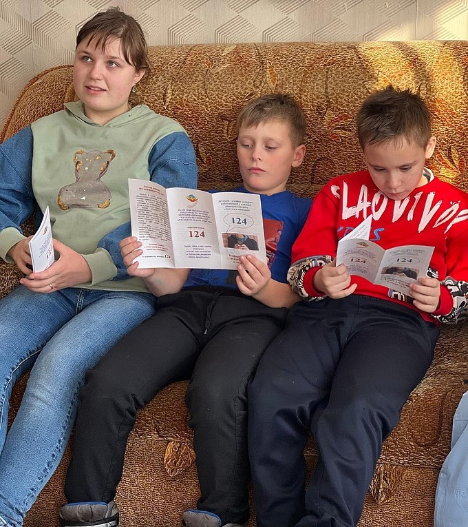 Дети читают буклеты с информацией о Детском телефоне доверия