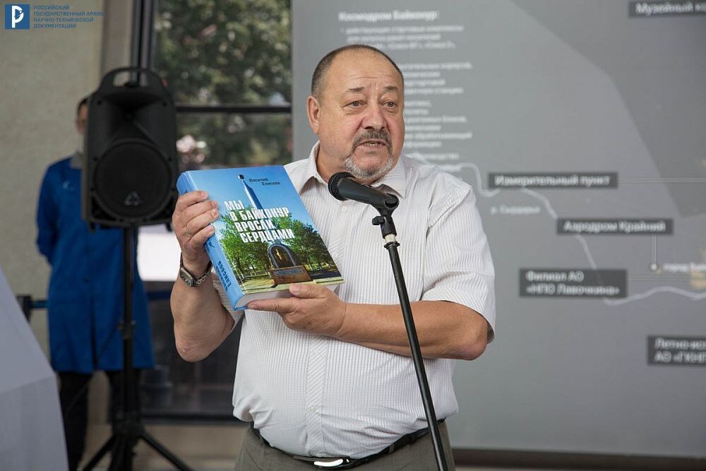 В.И. Елисеев – зам. председателя МОО ветеранов Байконура показывает свою книгу «Мы в Байконур вросли сердцами» на открытии выставки «Байконур. История и современность» в Центре «Космонавтика и авиация» ВДНХ. 2020 г. РГАНТД. Ф. 99. Оп. 90-31. Д. 16.