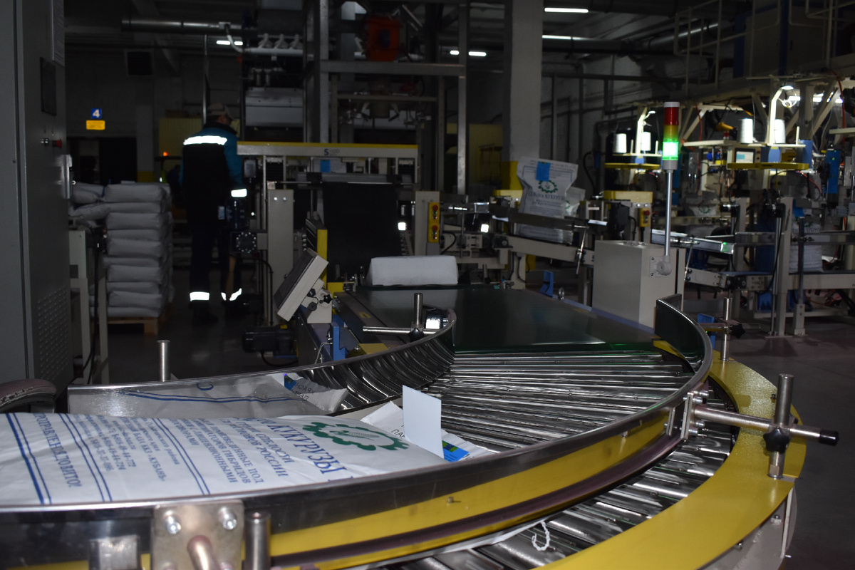 Работает японский робот-политайзер по расфасовке и упаковке в паллеты готовых семян гибридов кукурузы.