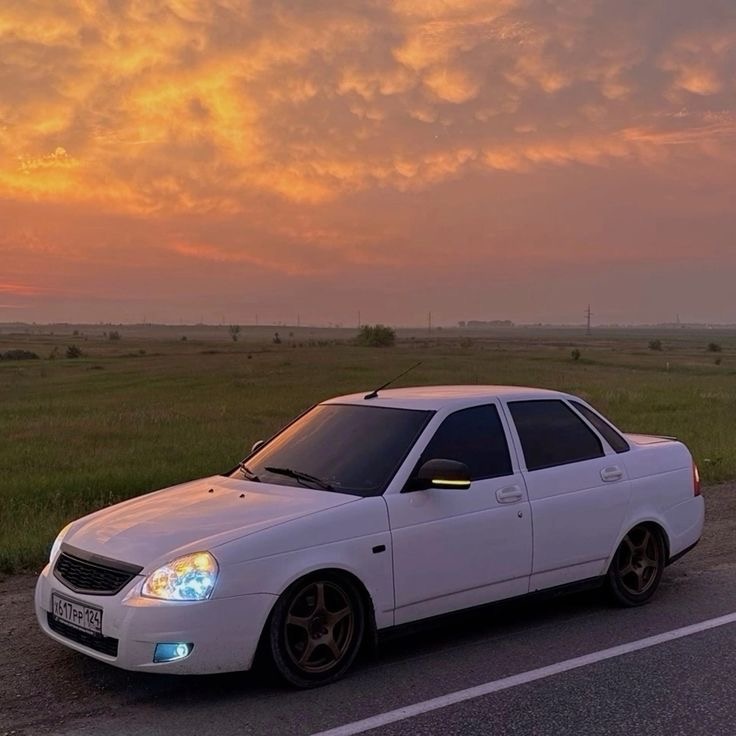 На фото Lada Priora с доработками (тонированные стёкла, заниженная подвеска, другие диски).

Плюсы:

✅ Низкая стоимость владения – дешёвые запчасти и обслуживание.
✅ Неплохая динамика – особенно с двигателем 1.6 (98-106 л.с.), машина лёгкая и бодро разгоняется.
✅ Простая конструкция – легко ремонтируется даже в гаражных условиях.
✅ Большое комьюнити – много информации по ремонту, тюнингу и настройке.
✅ Хорошая топливная экономичность – расход около 7-8 л/100 км.

Минусы:

❌ Качество сборки – возможны скрипы, слабая шумоизоляция, быстро изнашивается салон.
❌ Безопасность – слабые краш-тесты, минимум современных систем защиты.
❌ Электрика – бывает нестабильной, возможны глюки с проводкой и датчиками.
❌ Подвеска – штатная версия не очень комфортная, особенно на плохих дорогах.

С тюнингом некоторые минусы можно устранить, например, улучшить шумоизоляцию или поставить более мощный мотор. Но в целом Priora остаётся отличным бюджетным вариантом для тех, кто любит доработки и самостоятельный ремонт.