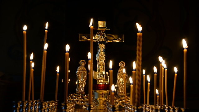 Зажженные свечи в церкви, символизирующие молитвы об усопших