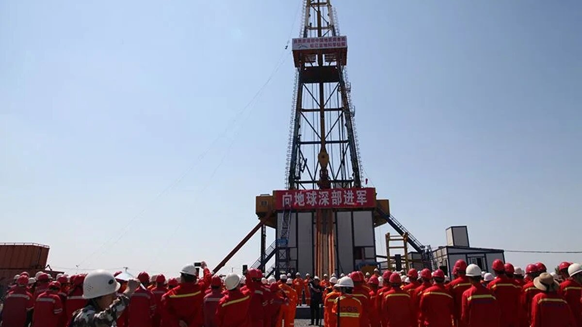 Рабочие стоят перед Songke 2, самой глубокой скважиной, когда-либо пробуренной в научных целях в Азии, в Анде, провинция Хэйлунцзян