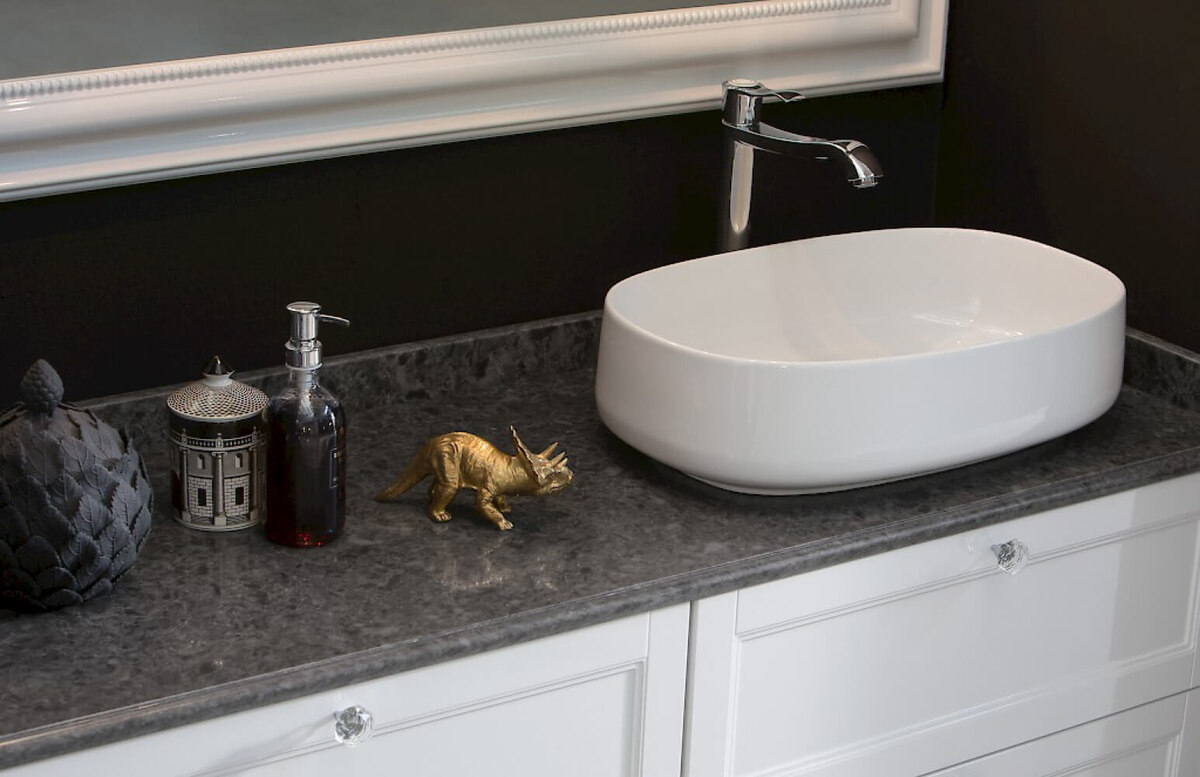 Глубокий темно-серый цвет столешницы из кварца Noble Imperial Grey от TechniStone подчеркивает белизну белого фарфора и деревянной тумбы со стеклянной фурнитурой