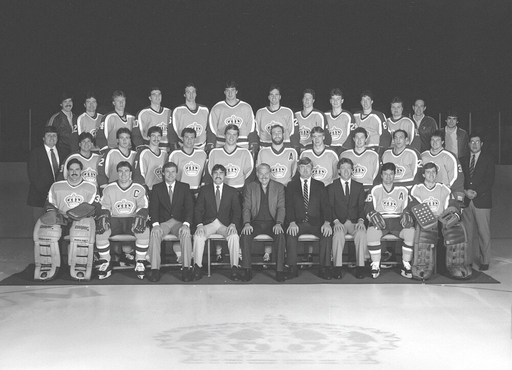  «Лос-Анджелес Кингз» 1985-86: Верхний ряд:   Марк О’Нилл (тренер), Моррис Лукович, Лэн Хэшборн, Син Макенна, Дин Кеннеди, Ларри Пфайфайр, Джо Паттерсон, Гранд Ледьярд, Аллан Туер, Брайан Уилкс, Брайан Эриксон, Пит Демерс (тренер), Ролли Родригез (сервисмэн).   Средний ряд:  Джон Вольф (администратор), Джим Фокс, Крейг Редмонд, Фил Сайкс, Марк Харди, Джон Келли, Джэй Уэллс, Берни Николлз, Гэри Гэлли, Дэйв «Тигр» Уильямс, Роланд Мелансон, Рон Муниц (координатор).   Нижний ряд:  Даррен Эллиот, Дэйв Тэйлор, Фил Мьюр (тренер), Рогасьен Вашон (Генеральный Менеджер), Джерри Басс (владелец команды), Пэт Куинн (главный тренер), Майк Мерфи (тренер), Марсель Дионн, Боб Янечик.