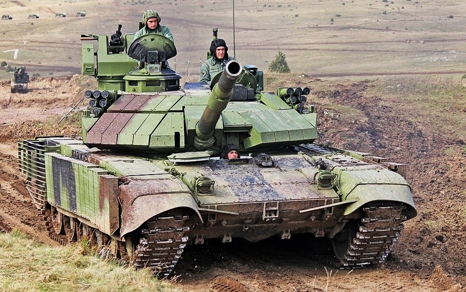 М-84AS2. Можно обратить внимание на погон командирской башенки увеличенной высоты в котором оборудованы дополнительные смотровые приборы, а также измененную конструкцию модулей ДЗ на ВЛД корпуса, обеспечивающая лучшее ее перекрытие.