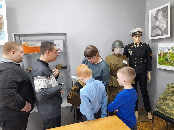 Сотрудник музея показывает детям обмундирование солдат