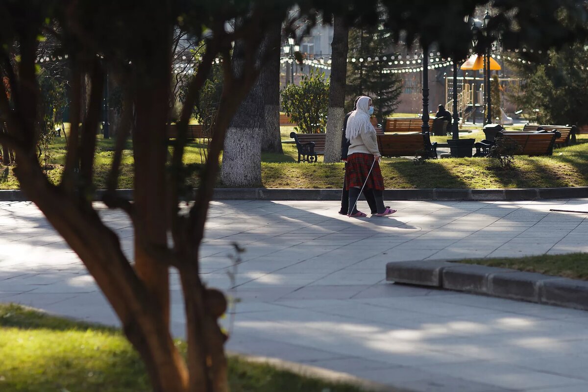 Эпидемия коронавируса - люди в масках солнечным днем гуляют зимой в парке © Sputnik / Alexander Imedashvili
