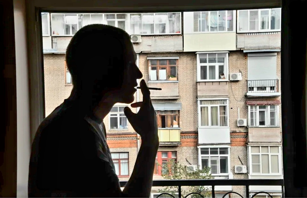 Курящий мужчина возле окна
