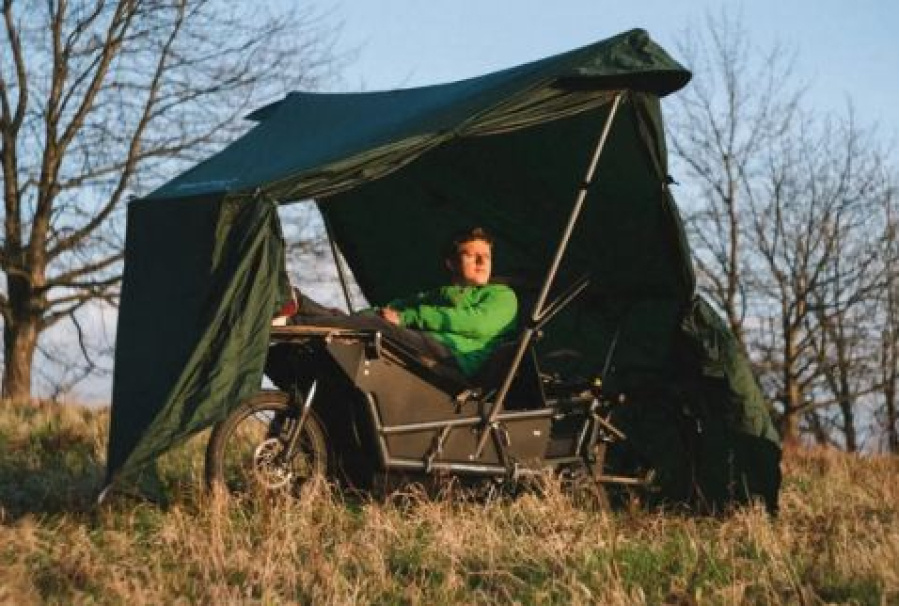 Представлен уникальный велосипед, который сочетает в себе функции палатки и рабочего пространства, что делает его идеальным для любителей активного отдыха. Инженеры компании Spacecamper разработали устройство, которое можно использовать для поездок, ночевок и работы на свежем воздухе. Этот электровелосипед позволяет не только передвигаться, но и комфортно отдыхать в любой обстановке.Spacecamper Bike является инновационным электрическим грузовым велосипедом, который включает в себя встроенную палатку. Разработчики стремились создать удобное решение для кемпинга, сохраняя мобильность обычного велосипеда. В отличие от традиционных велокемперов, которые используют громоздкие прицепы или отдельные конструкции, данный велосипед интегрирует все необходимое в свою раму, что значительно упрощает его использование.На базе Spacecamper Bike находится электрический грузовой велосипед Riese & Müller Load4 75. Он обладает алюминиевой рамой и мощным электродвигателем Bosch с функцией педального ассистента. Запас хода варьируется от 80 до 160 км в зависимости от выбранной конфигурации аккумуляторов, а максимальная скорость достигает 45 км/ч, что делает поездки на нем довольно динамичными и удобными.Одной из главных особенностей данного велосипеда является система трансформации для сна. Он оборудован складным креслом, которое при необходимости превращается в кровать размером 195 на 56 см, и может быть дополнено надувным матрасом. Важной деталью является возможность откидывания руля, что освобождает пространство для раскладки спального места, позволяя владельцу делать это, не вставая с сиденья. Палатка, изготовленная из прочного силиконизированного нейлона, крепится к велосипеду и легко разворачивается в защищенное укрытие, обеспечивая комфорт даже в плохую погоду.