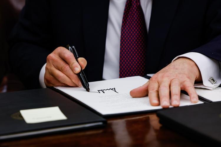 Президент Дональд Трамп подписывает исполнительные указы в Овальном кабинете 20 января 2025 года. Анна Манимейкер/Getty Images