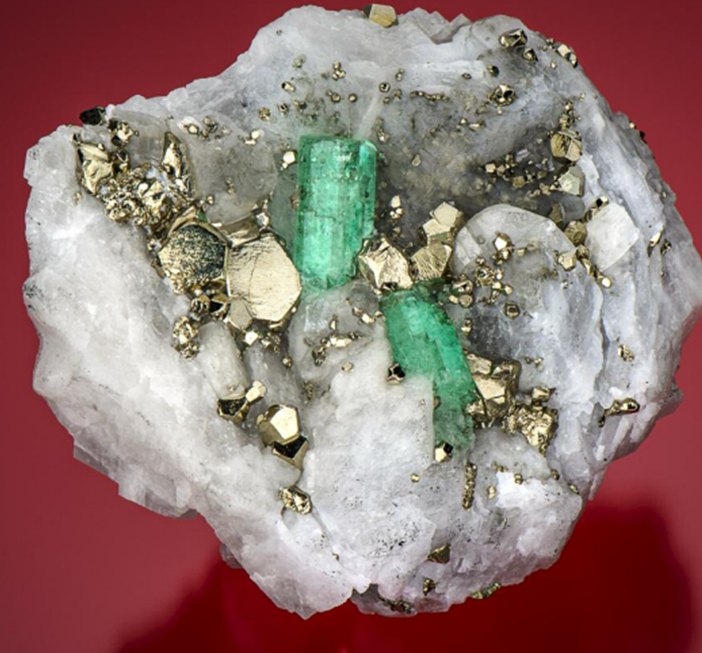 Образец изумруда из Чивора, Колумбия. Карбонатная матрица содержит вуг с изумрудом и пиритом. Верхний изумруд имеет размеры 16,82 × 8,55 мм, нижний изумруд — 11,98 × 7,96 мм. Образец имеет размеры 76,43 × 63,44 мм. Фото Роберта Уэлдона/GIA