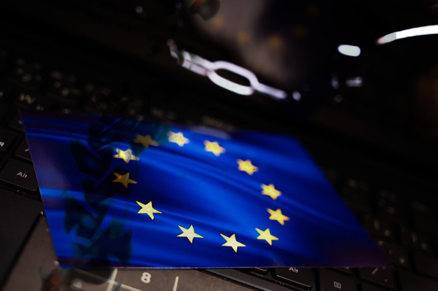 Изображение рук в наручниках на экране ноутбука рядом с флагом ЕС. Руслан Яроцкий/URA.RU/ТАСС