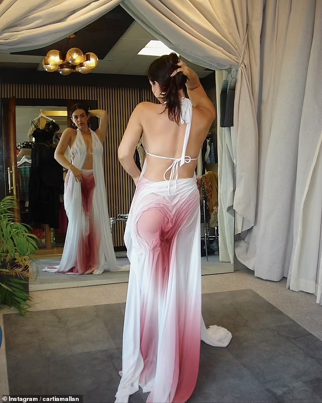 Брюнетка примеряла белое платье в пол с красновато-розовым оттенком на юбке