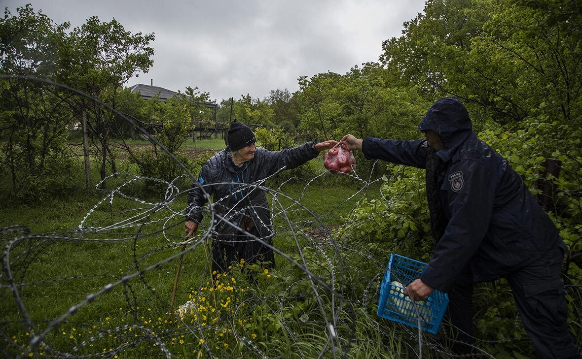 Грузинская пограничная полиция передает еду через забор из колючей проволоки местной жительнице, которая проживает на территории контролируемой Южной Осетией в селе Хурвалети(Фото: Daro Sulakauri / Getty Images)