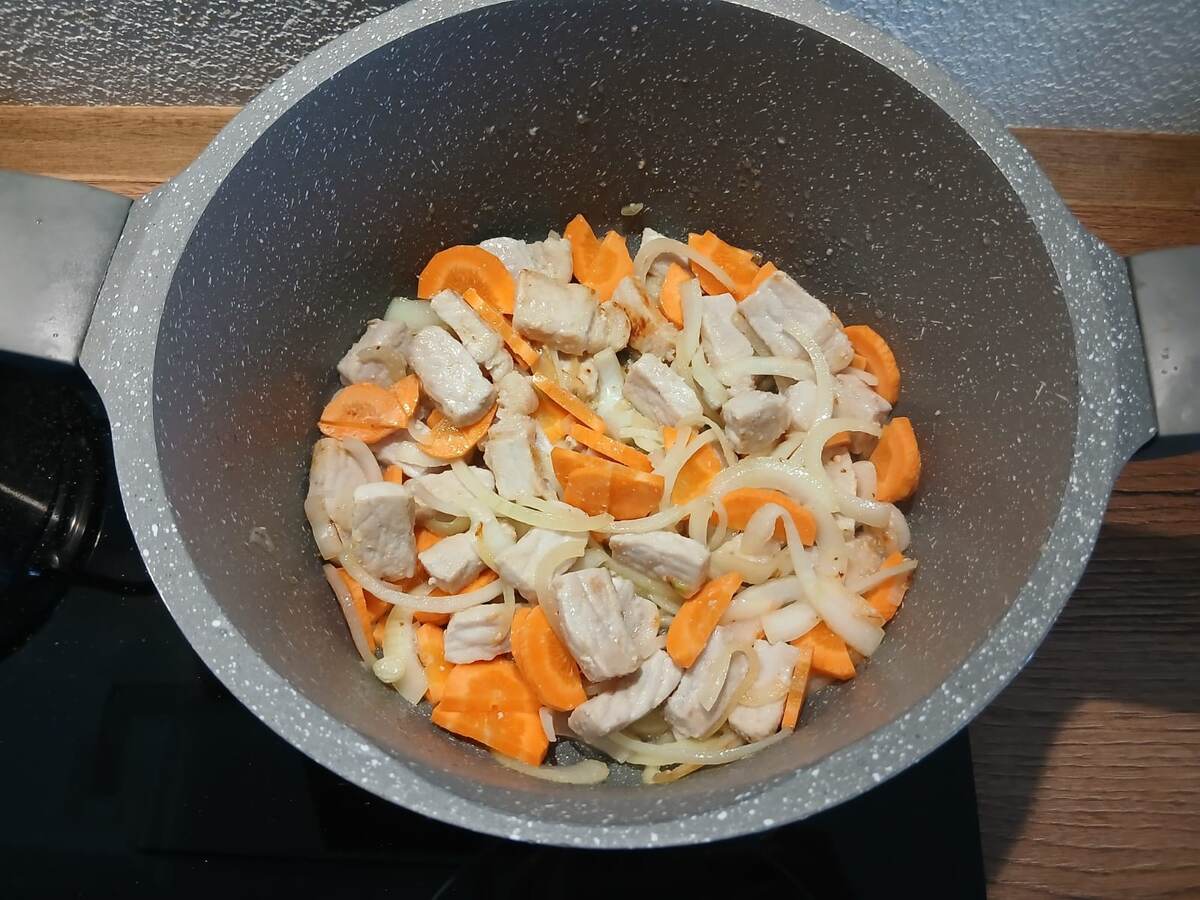 Лук и морковь — дуэт, который нельзя пропустить. Шинкую лук полукольцами, морковь режу полукольцами и высыпаю к мясу. Аромат — как из печи деревенской хаты!