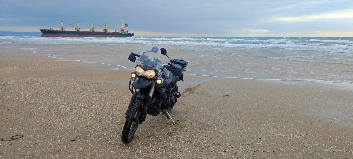 На фоне огромного сухогруза, севшего на мель