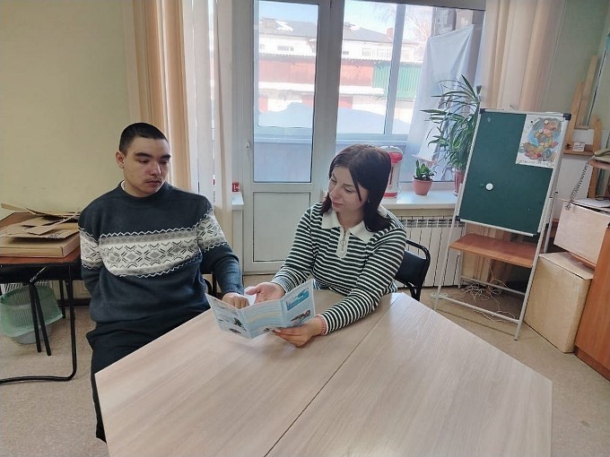 Конькова Яна Константиновна показывает мальчику подростку буклет «Будьте осторожны зимой!»