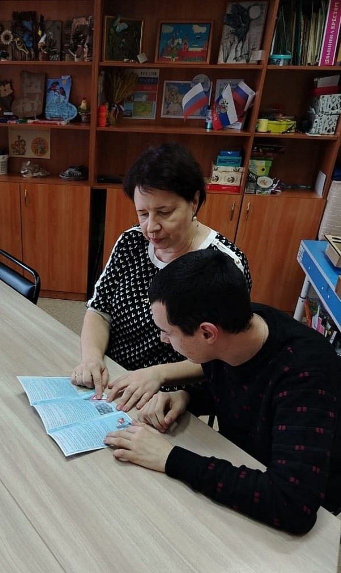 Некрасова Татьяна Николаевна показывает мальчику подростку буклет «Будьте осторожны зимой!»