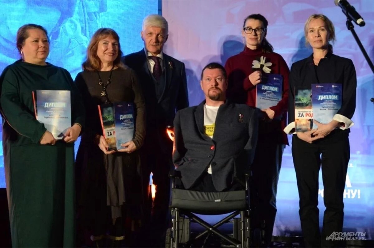    Герой России Максим Бахарев лишился в боях рук и ног, но не пал духом. На фото он вместе с авторами рассказов из нового сборника.