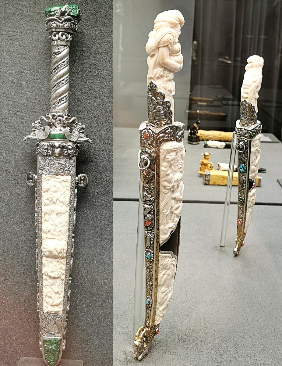 Кинжал в ножнах "Античный", коллекция "Греческие мотивы", ножи в ножнах мужской и женский "Восточные мотивы", Москва, 2023, Мастера Нишанов А., Караходжаева Т., Добрин Е. (клинок).        Дамасская сталь, белый металл, бивень мамонта, орех, малахит, литьё, резьба, гравировка, инкрустация, тонирование.                                                                                                                              Сталь, белый металл, бивень мамонта, граб, малахит, кораллы, бирюза, резьба, гравировка, инкрустация, золочение, тонирование.