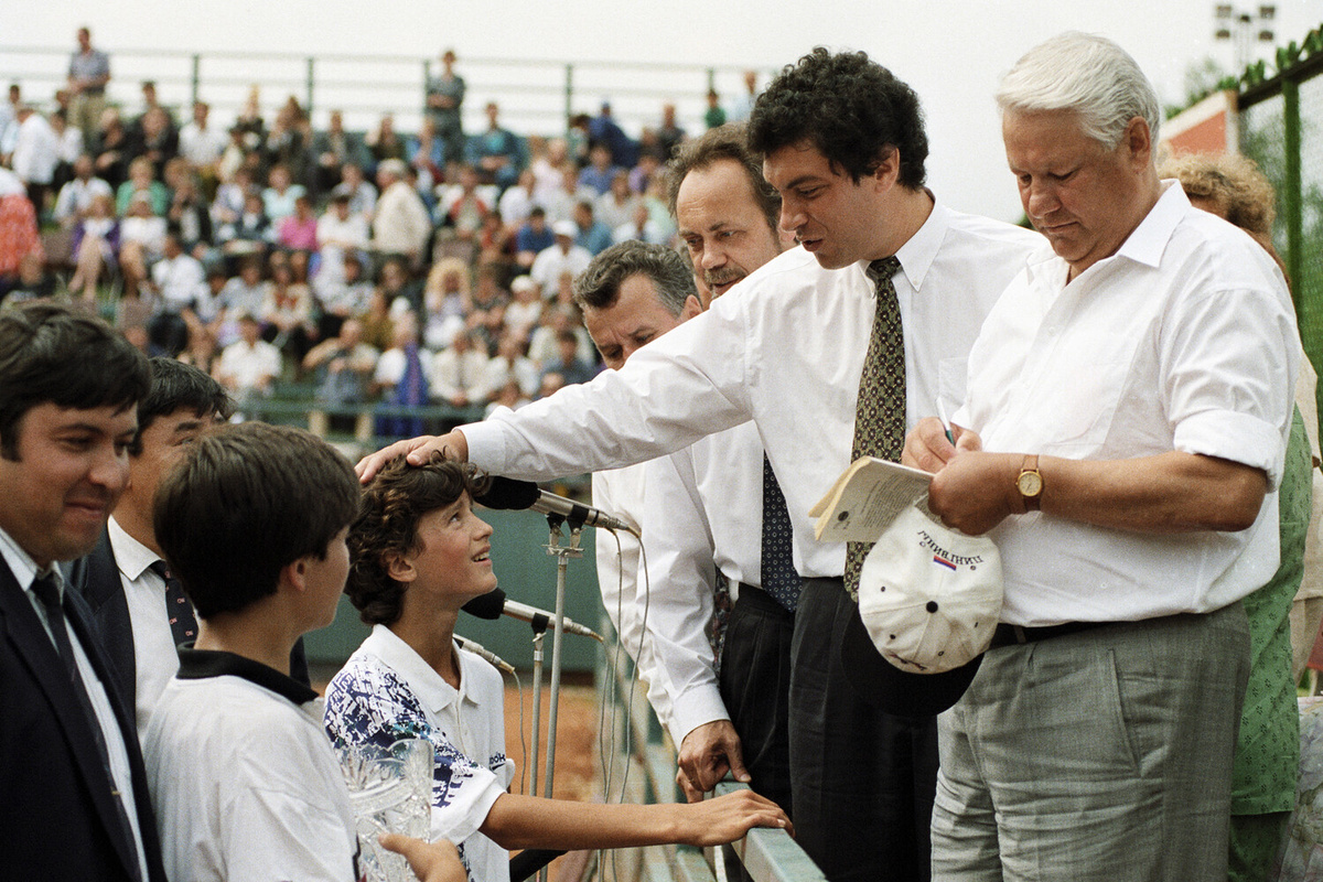 Президент России Борис Ельцин (справа) дает автограф юному теннисисту на детском спортивном празднике теннисистов на новых кортах в саду А. С. Пушкина. Слева — губернатор Нижнего Новгорода Борис Немцов, 1994 год ©Дмитрий Донской/РИА Новости  📷