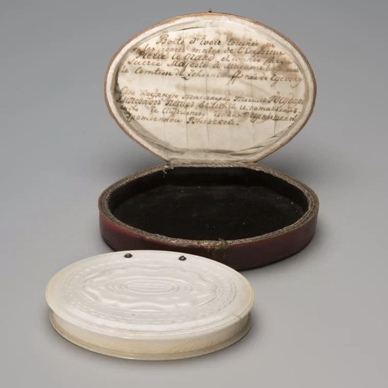 Табакерка овальная в футляре, автор Пётр I, нач. 1710-х - сер. 1720-х гг, слоновая кость, металл, сафьян, атлас, бархат; токарная обработка, размеры: 1,5х8,7х6 см (табакерка); 2,8х10х7,2 см (футляр)
