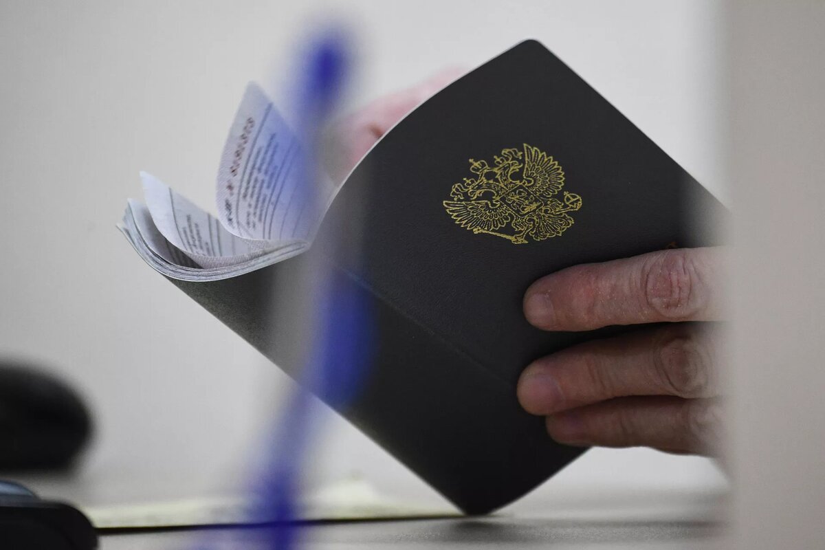 Сотрудник центра занятости населения держит в руках трудовую книжку посетителя