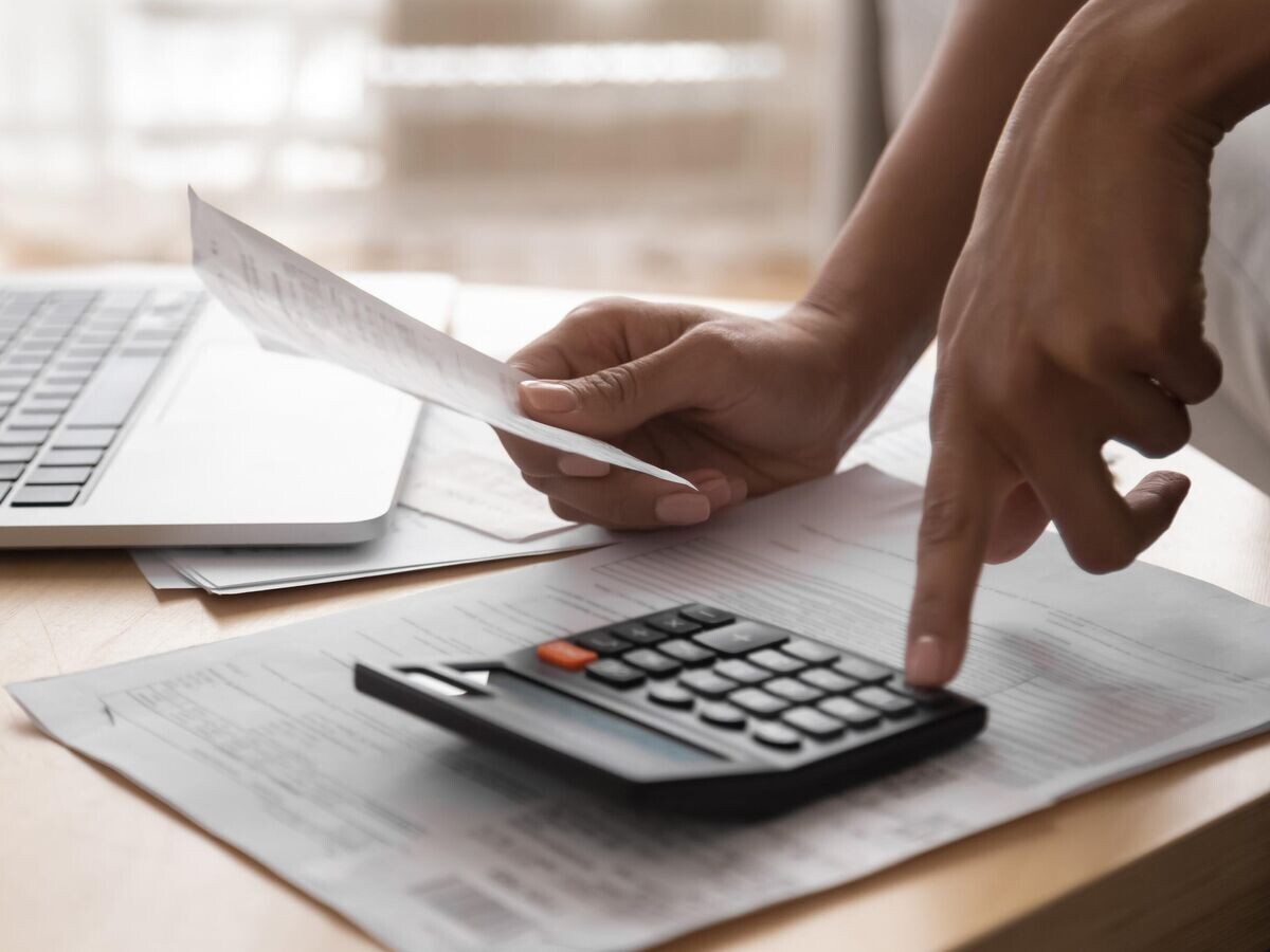    Женщина считает стоимость налога на долговой кредит на калькуляторе© iStock.com / fizkes