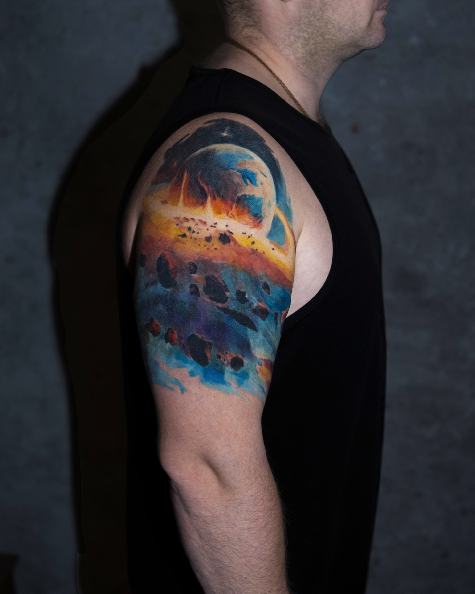 Татуировка на плече на тему космоса, идеально подчеркивает анатомию тела выглядит ярко и эффектно 