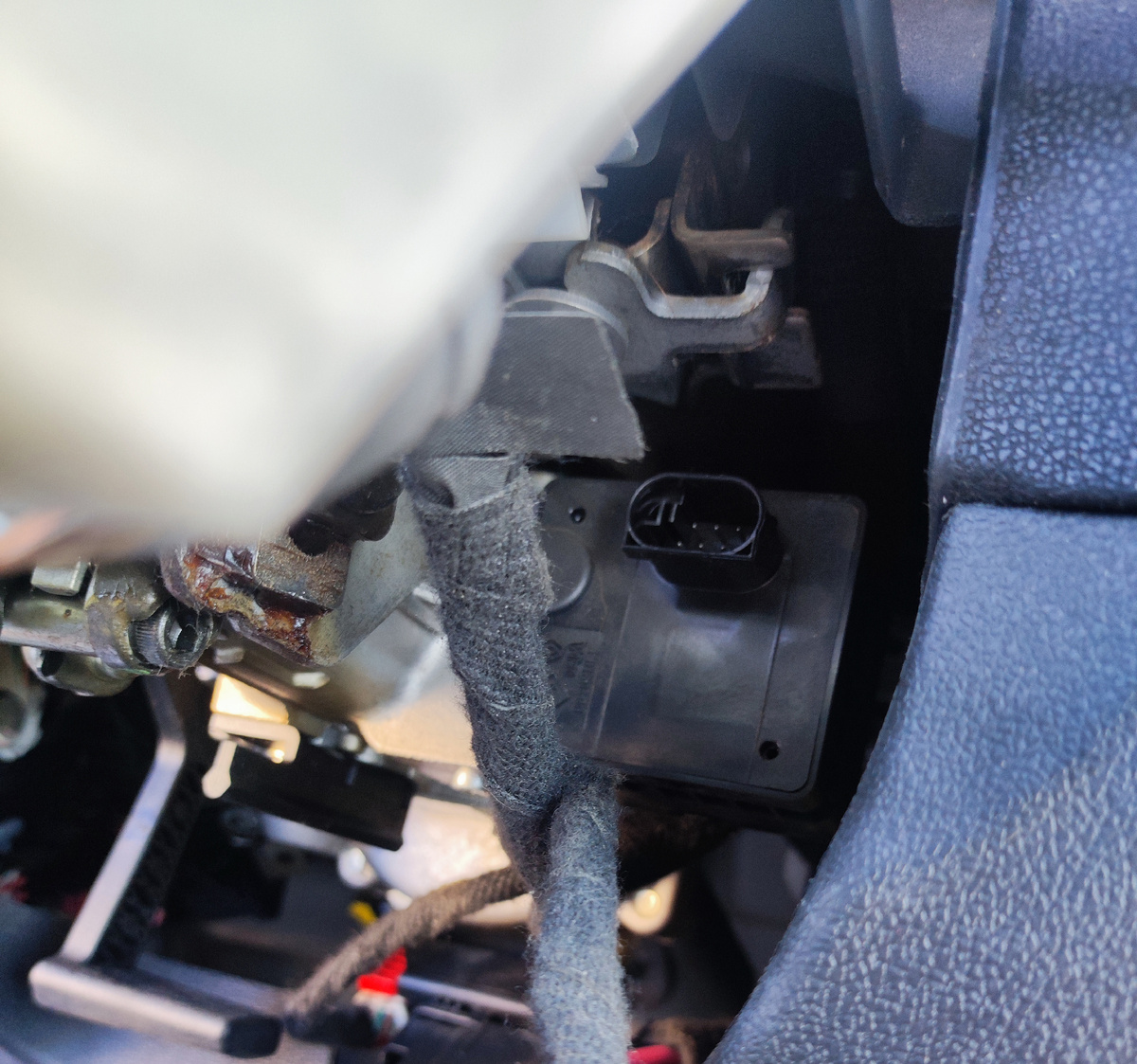 Механизм защелки находится справа от рулевого вала - достать до него, не снимая кожух, сложно.