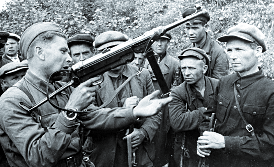 Командир партизанского отряда учит бойцов обращаться с трофейным MP-40.