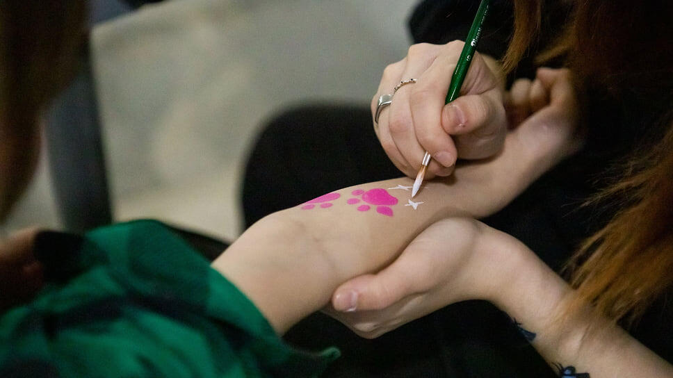 Волонтер, рисующий на руке ребенка.📷Фото: Ксения Федорова / Коммерсантъ