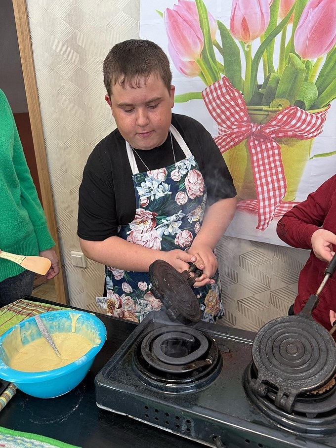 Мальчик переворачивает сковороду на плите