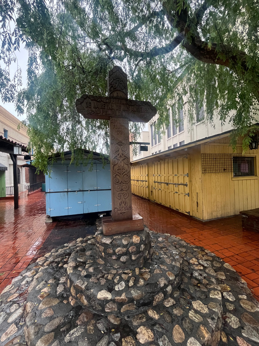 Деревня (el Pueblo)  «Королевы Ангелов» была основана прям на этой площади в 1781 году, и это самое место — центр первоначальной деревни — отмечено крестом. Когда мы подошли сюда, у креста стояла мексиканская женщина. Она положила на него руку и о чём-то тихо молилась. 