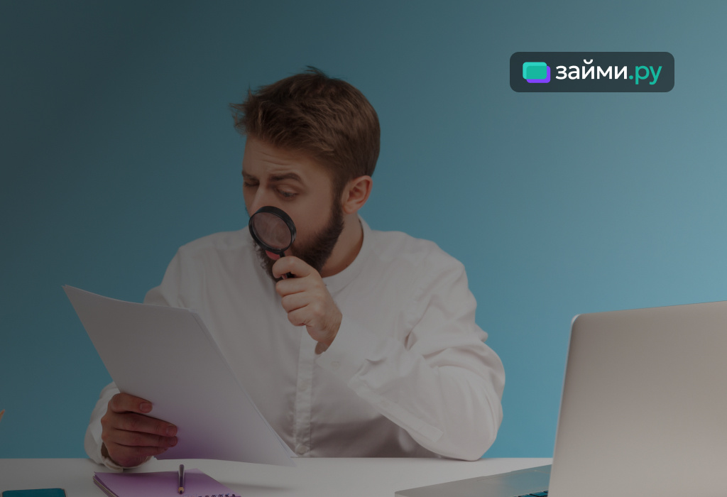 Человек с лупой внимательно изучает условия кредитного договора, выделяя важные пункты о ставках, переплатах и рисках