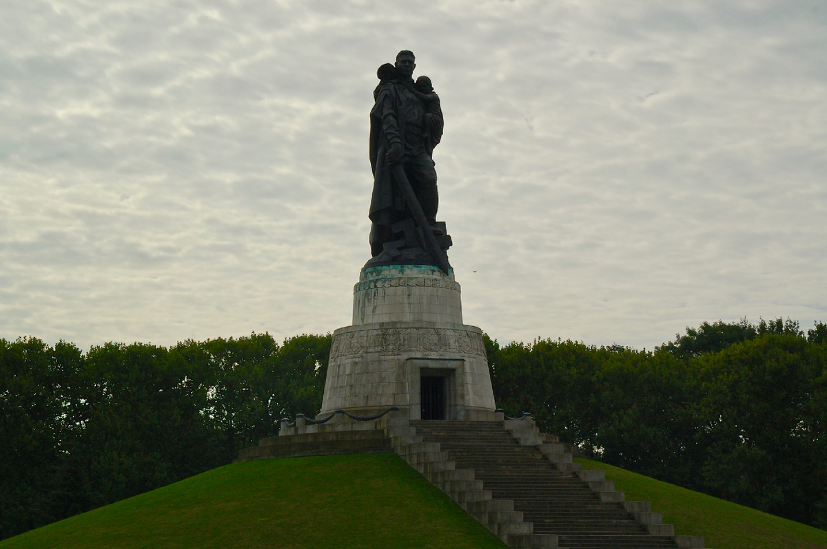 В одной руке он держит спасённую немецкую девочку, в другой — меч, разрубающий поверженную свастику.