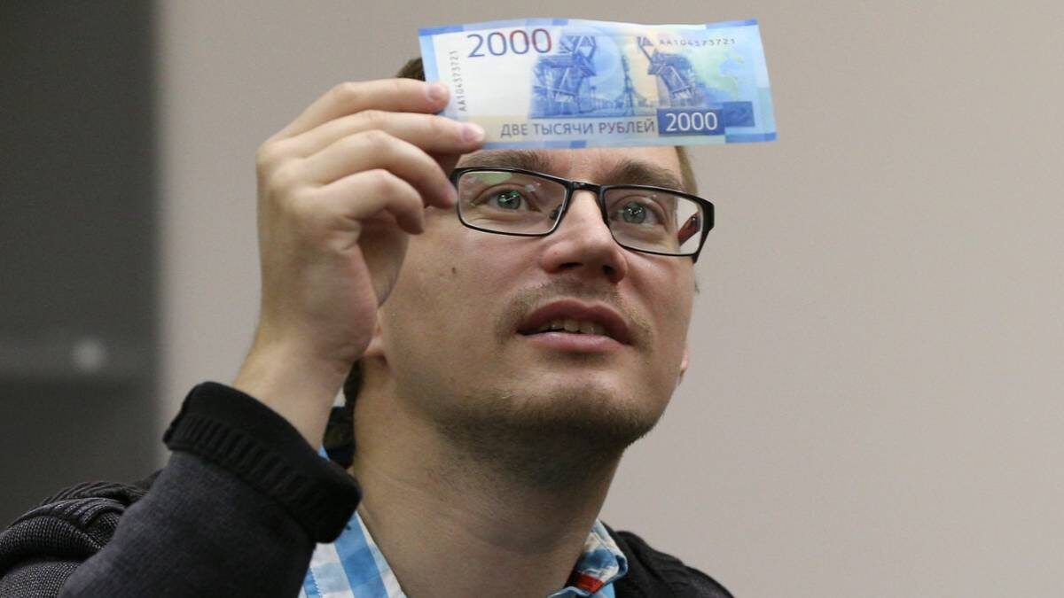    Внимательно рассмотрев банкноту на просвет, можно проверить ее подлинность / Фото: Гавриил Григоров / ТАСС