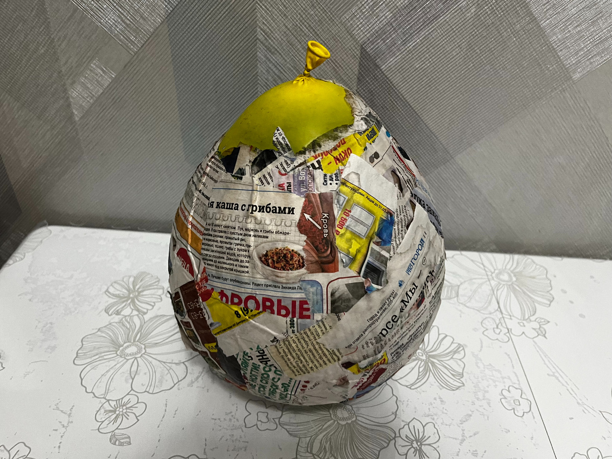 Надули шарик. Нанесли крем для рук. Затем обклеивали кусочки газеты, используя клей для обоев. Высыхал постепенно, ушло 2 дня.