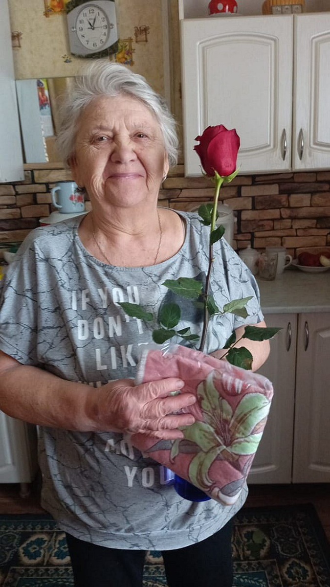 Пожилая женщина с подаренным ей цветком
