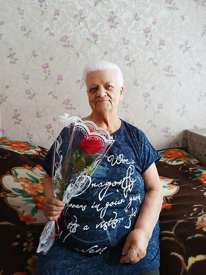 Пожилая женщина с подаренным ей цветком