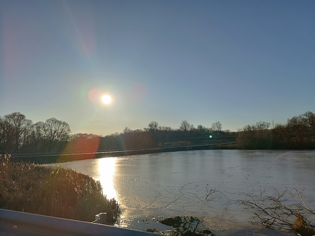 Лëд на пруду блестит в лучах рассвета
