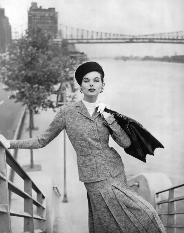 Энн Сент-Мари в классическом твидовом костюме с узором из бересты черного, бежевого и серо-коричневого цветов от Davidow, клетчатой ​​сумке-попоне от Gucci, коричневой шапке из бобрового фетра от Sally Victor, фото Генри Кларка, Vogue, 1 августа 1955 г.