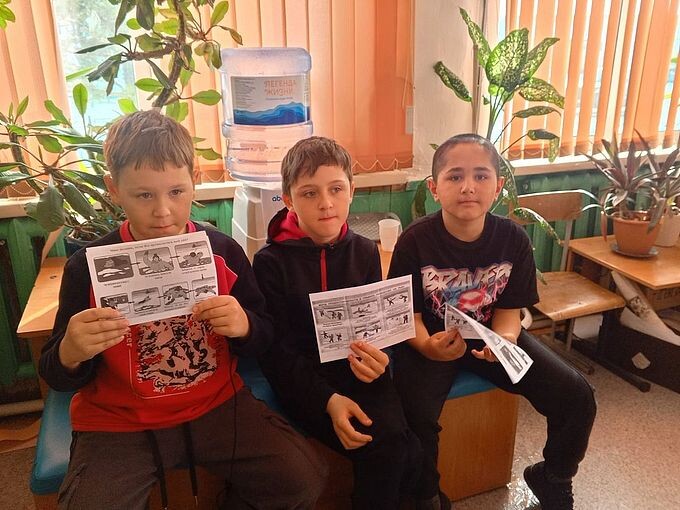 Три мальчика держат в руках выданные им буклеты