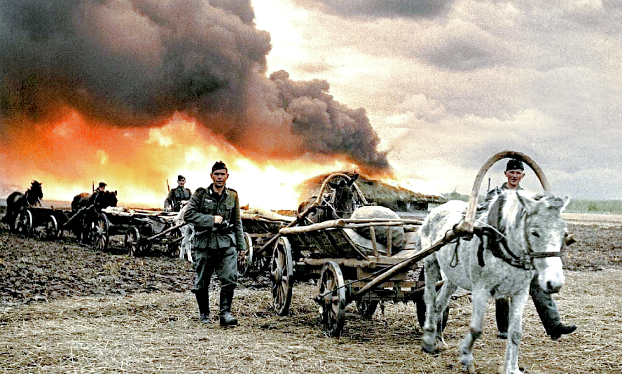 Солдаты вермахта с конными упряжками движется мимо горящего села. УССР, 1943 г.