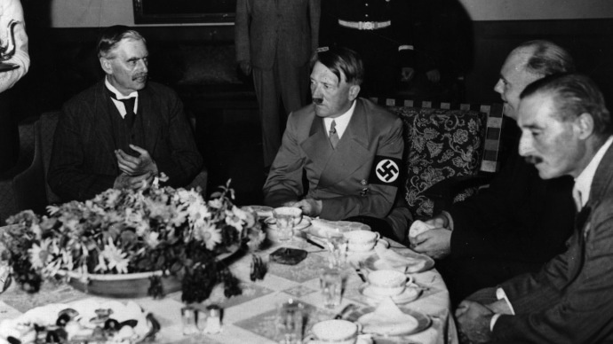 Изображение предоставлено: британский премьер-министр Невилл Чемберлен (слева) (1869–1940) и Адольф Гитлер (1889–1945) со своим переводчиком Паулем Шмидтом и Невиллом Хендерсоном (справа) за ужином во время визита Чемберлена в Мюнхен в 1938 году. (Фото Генриха Хоффмана/Getty Images)