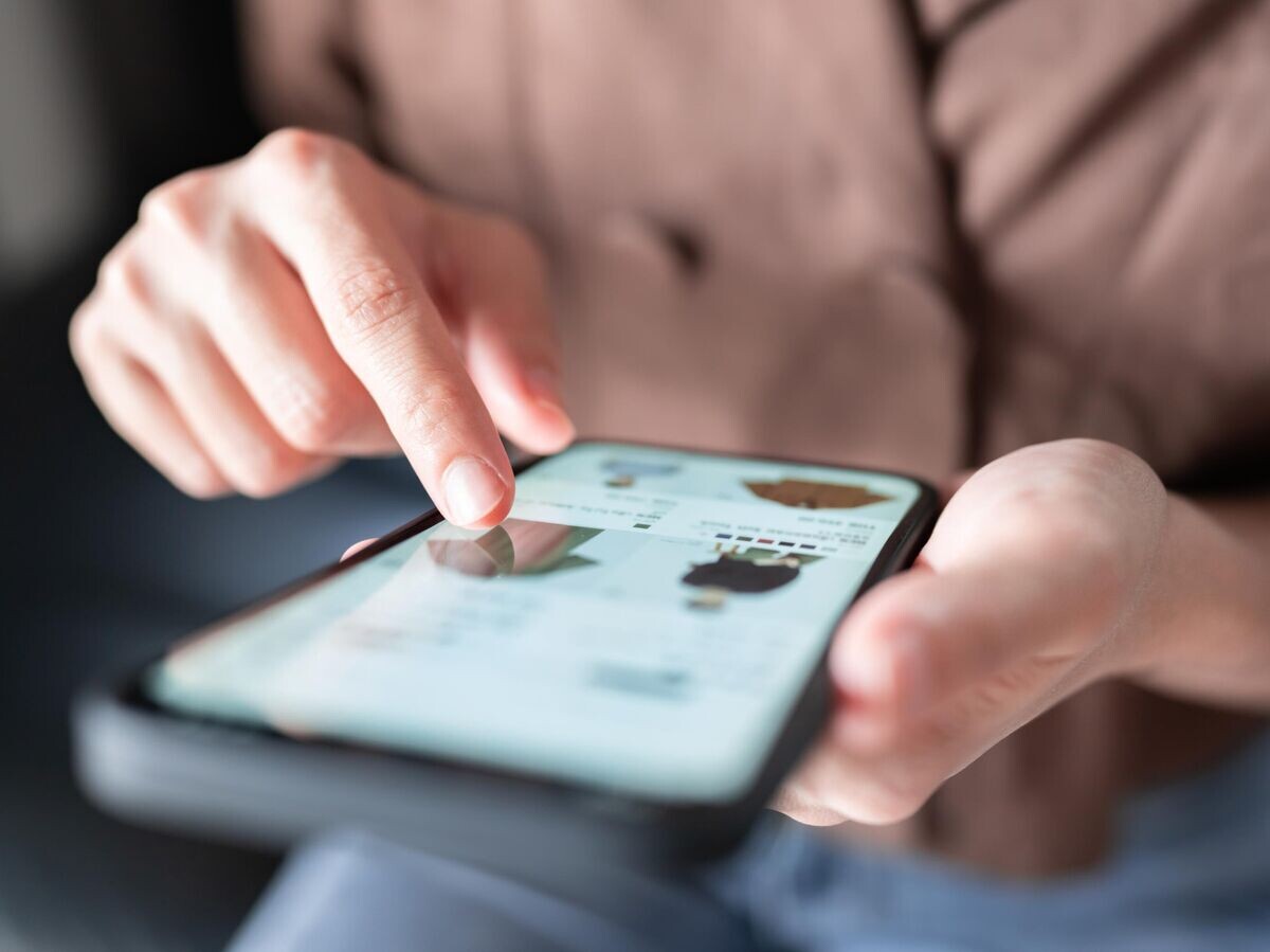    Девушка смотрит рекламу магазина в смартфоне © iStock.com / oatawa