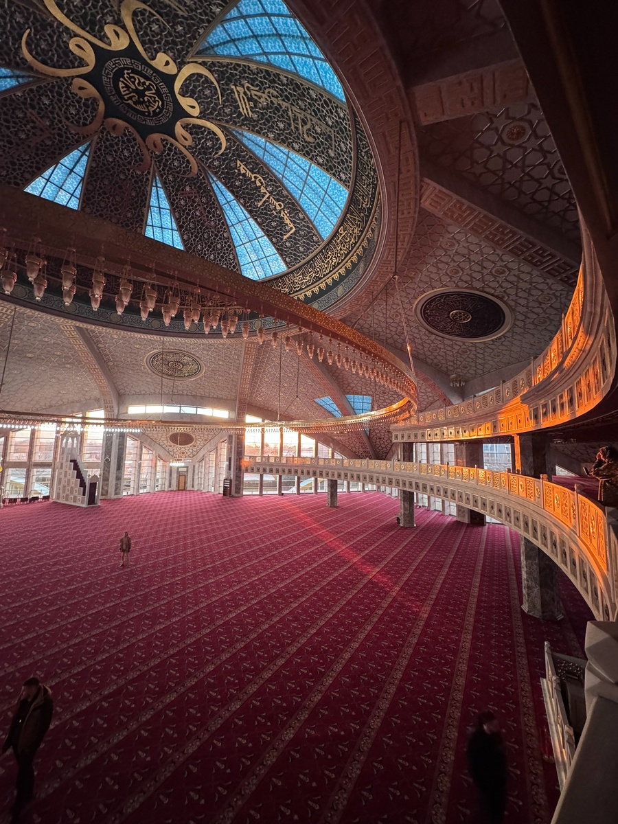  Округлая ,необычная форма с панорамным остеклением , создает иллюзию, что огромная летающая тарелка приземлилась в центре города! А ночью она оживает , благодаря невероятному освещению и видна за много километров. Внутри ,каждый элемент декора выполнен с любовью, купол расписан чистейшим золотом, орнаментом из красивейших цветов , а через окна свет заливает все пространство. Главное украшение мечети -люстра , в виде огромного полумесяца , диаметром 31 метр и весом в 5 тонн.  Она построена в честь матери Рамзана Кадырова, Аймани Кадыровой и олицетворяет любовь каждого СЫНА к своей МАТЕРИ !